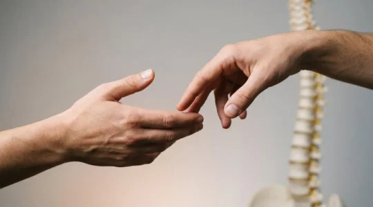 Two hands performing different manual therapy techniques on the human spine, highlighting the contrast between osteopathic and chiropractic approaches