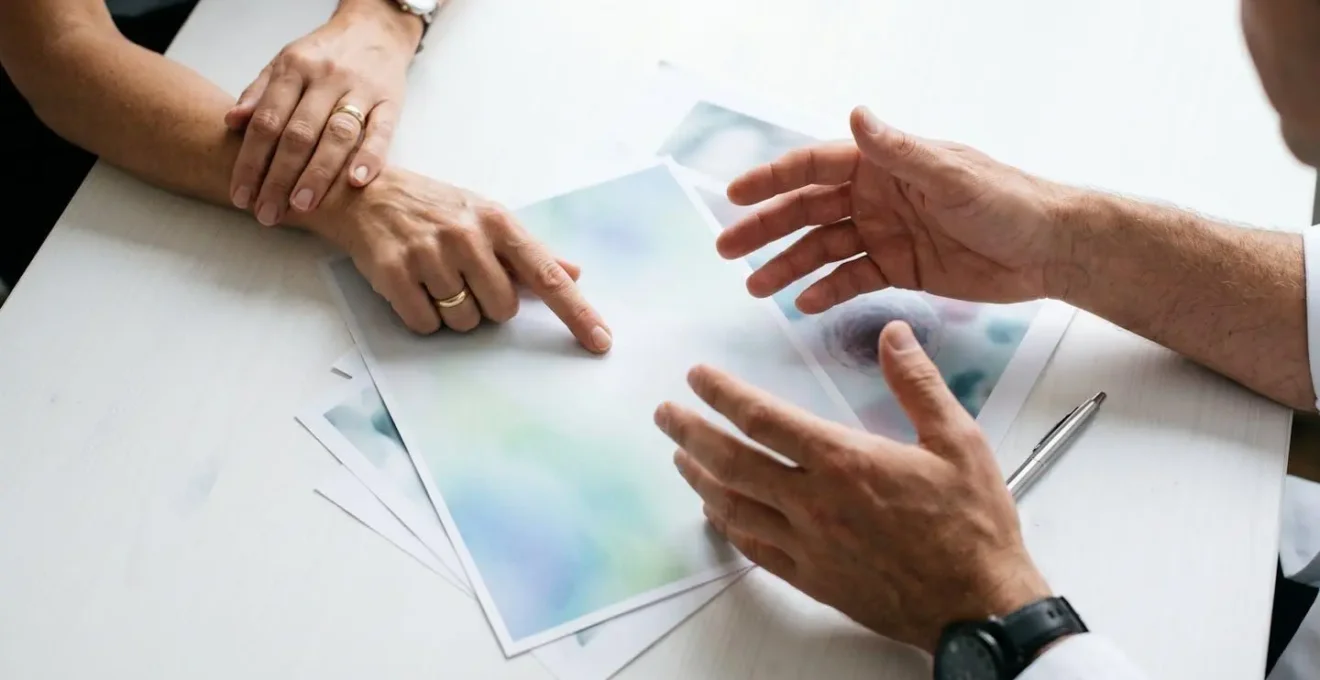 Two sets of hands reviewing medical documents side by side on clean desk