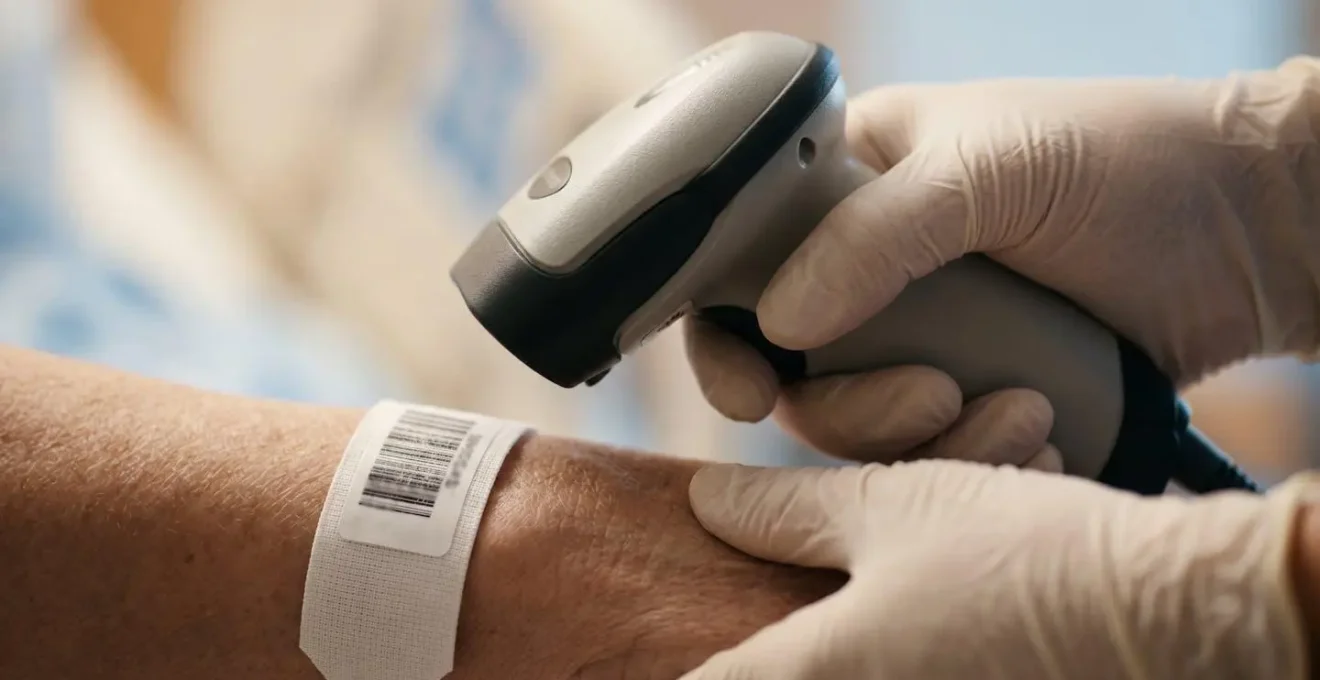 Nurse's hands performing barcode medication verification process with patient wristband in hospital setting