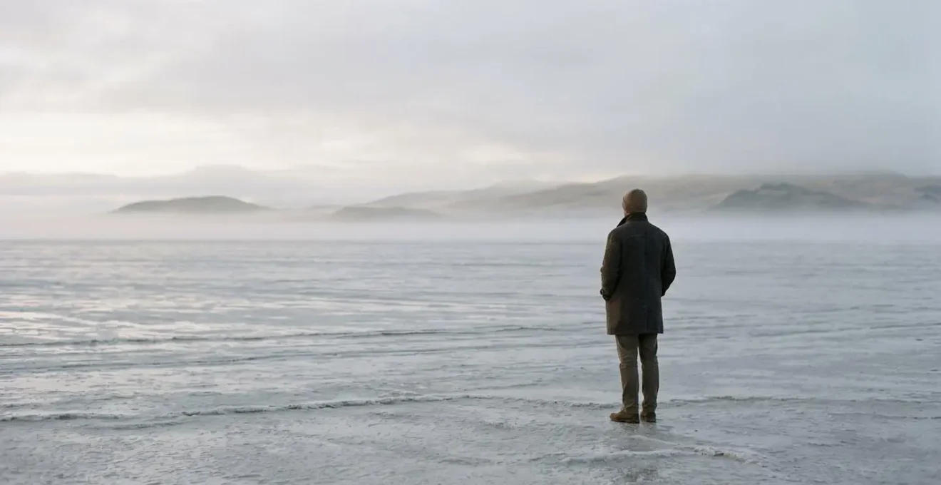 Environmental photograph showing a solitary figure in a vast minimalist landscape representing the frozen state of unresolved trauma